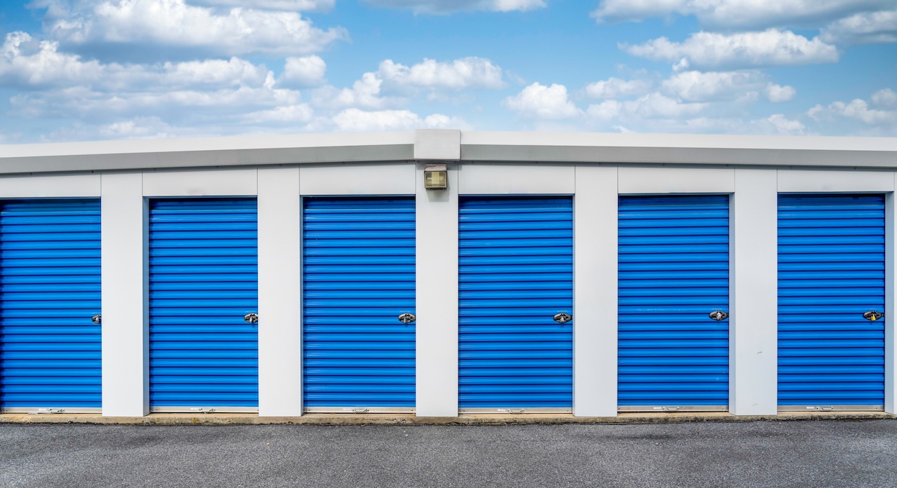 Six blue roll-up storage units under a cloudy sky at Greenville Easy Storage