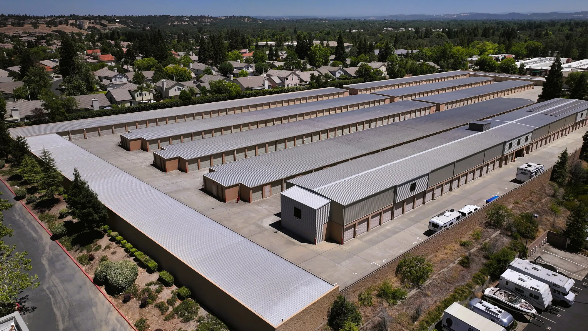 Aerial view across Sierra College Self Storage from the rear of the property, looking over rows of drive-up units toward the Roseville foothills