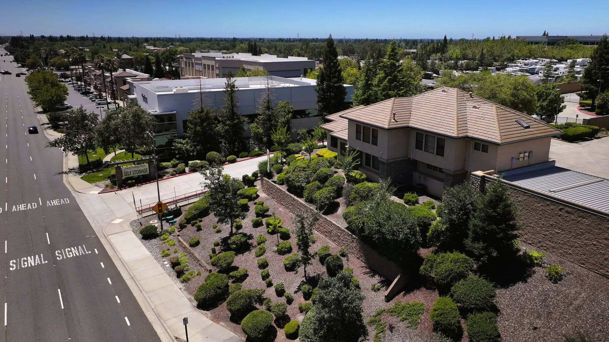 Aerial view of the Sierra College Self Storage entrance off Sierra College Boulevard, with the street sign and the landscaped slope below the office