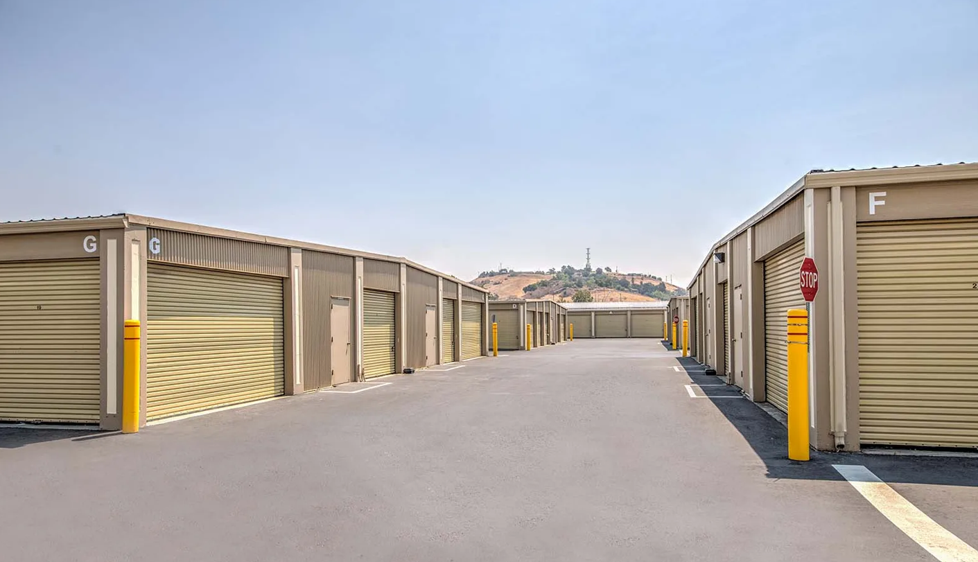 Wide drive-up aisle between buildings F and G at Willow Glen Storage, hills in the distance